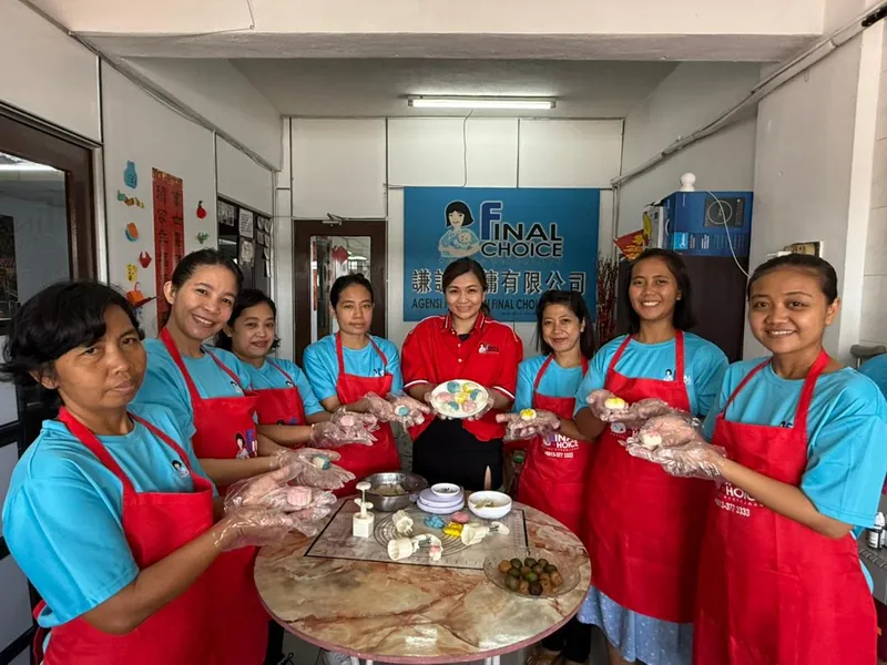 Eight trainees in Final Choice aprons gathered around a table during a practical session at our office