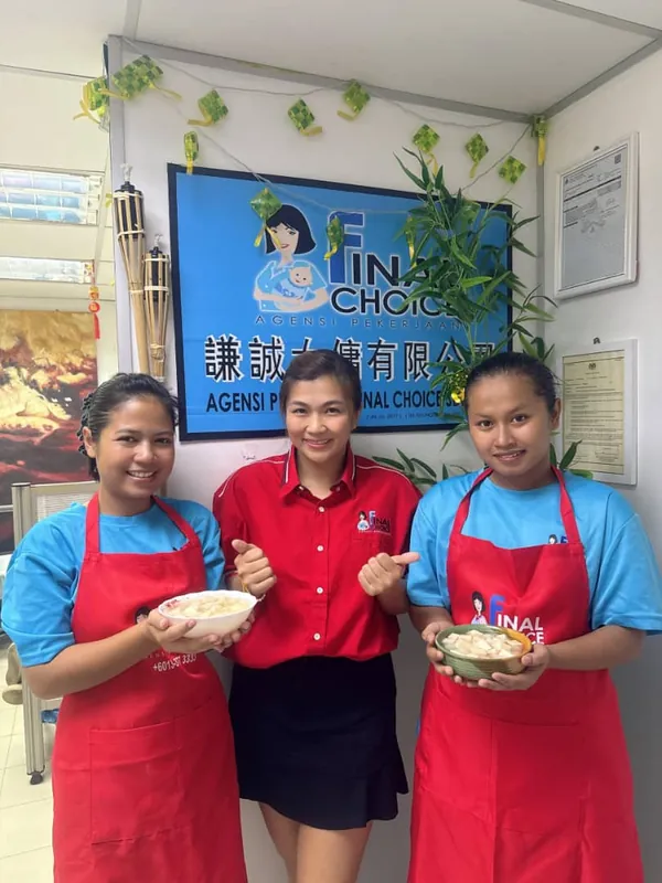 A Final Choice team member in a red blouse with two trainees holding bowls of food