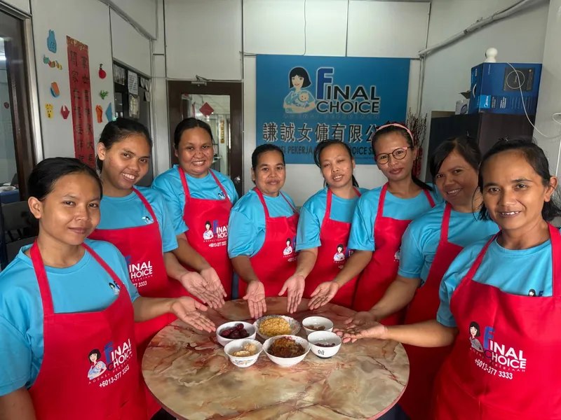 Trainees in Final Choice aprons showing their hands over a table of ingredients and bowls at a cooking session